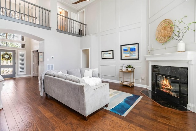 10601 Showboat Cv, Austin, TX 78730 - living area featuring a high end fireplace, a towering ceiling, dark wood-style flooring, arched walkways, and ceiling fan