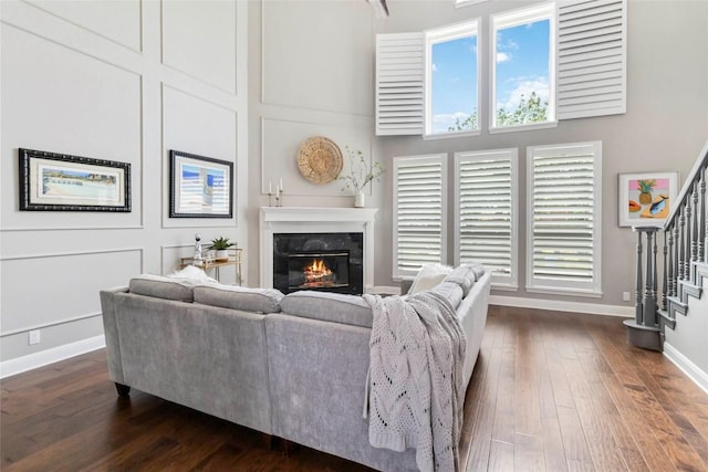 10601 Showboat Cv, Austin, TX 78730 - living area featuring a glass covered fireplace, stairway, dark wood-type flooring, healthy amount of natural light, and a towering ceiling