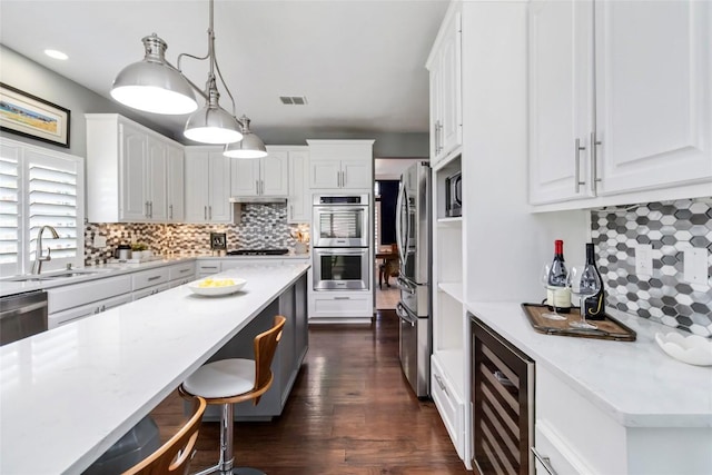 10601 Showboat Cv, Austin, TX 78730 - kitchen with beverage cooler, appliances with stainless steel finishes, white cabinetry, backsplash, and recessed lighting