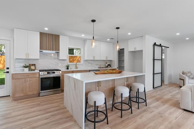 5604 Overbrook Dr, Austin, TX 78723 - kitchen featuring stainless steel appliances, a barn door, recessed lighting, tasteful backsplash, and light countertops