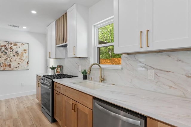 5604 Overbrook Dr, Austin, TX 78723 - kitchen with stainless steel appliances, light stone counters, light wood-type flooring, white cabinetry, and backsplash