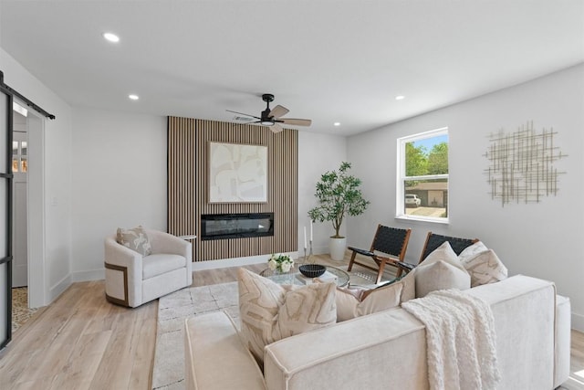 5604 Overbrook Dr, Austin, TX 78723 - living room with light wood-style floors, a barn door, recessed lighting, a ceiling fan, and a glass covered fireplace