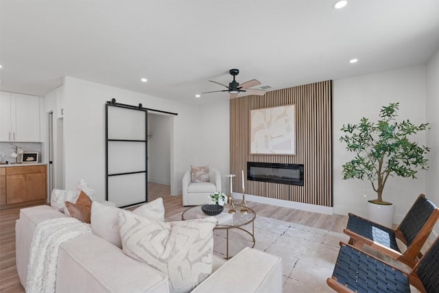 5604 Overbrook Dr, Austin, TX 78723 - living area with a barn door, recessed lighting, ceiling fan, light wood-style floors, and a glass covered fireplace