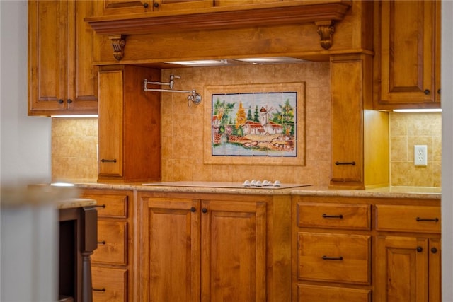 758 Mission Hts, New Braunfels, TX 78130 - kitchen view of pot filler, brown cabinetry, decorative backsplash, light stone countertops, and stovetop