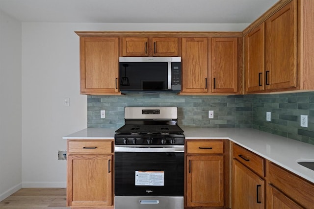 17129 Hamilton Point Cir, Manor, TX 78653 - kitchen with stainless steel gas range, light countertops, light wood-style floors, and decorative backsplash