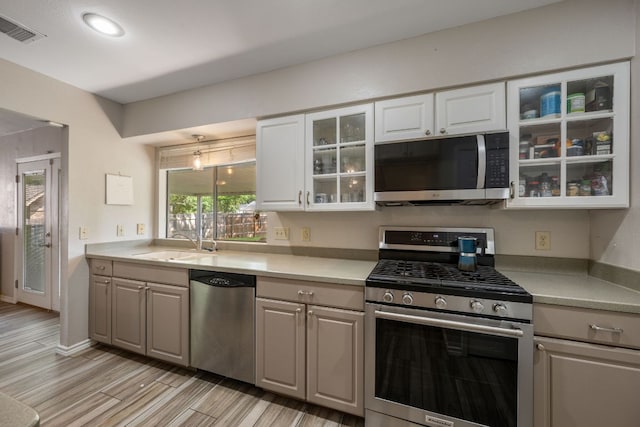 1300 Neans Dr, Austin, TX 78758 - kitchen with stainless steel appliances, light countertops, glass insert cabinets, light wood finished floors, and white cabinetry