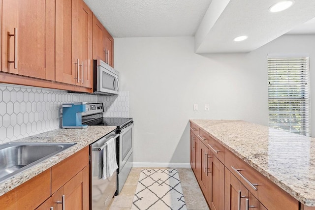 7685 Northcross Dr Unit 720, Austin, TX 78757 - kitchen featuring stainless steel appliances, tasteful backsplash, brown cabinetry, a peninsula, and light tile patterned floors