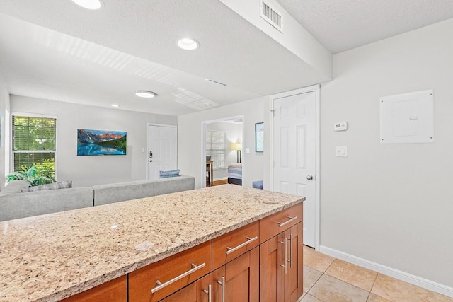 7685 Northcross Dr Unit 720, Austin, TX 78757 - kitchen with light stone counters, brown cabinetry, open floor plan, electric panel, and recessed lighting