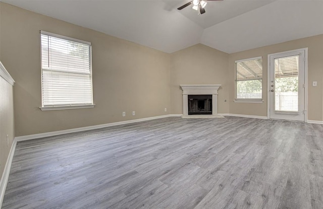 430 Zebra Dr, Kyle, TX 78640 - unfurnished living room featuring ceiling fan, wood finished floors, a fireplace with raised hearth, and vaulted ceiling