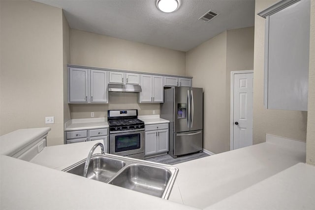 430 Zebra Dr, Kyle, TX 78640 - kitchen featuring appliances with stainless steel finishes, under cabinet range hood, light countertops, a textured ceiling, and gray cabinets