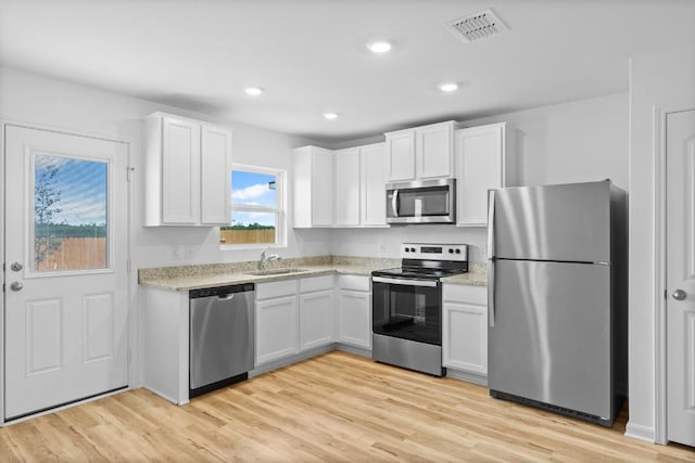470 Aplite Pass, Maxwell, TX 78656 - kitchen featuring appliances with stainless steel finishes, white cabinets, light wood-style floors, recessed lighting, and light stone counters