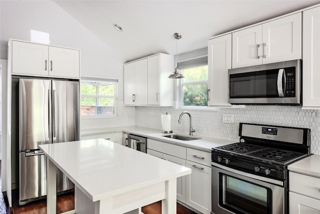 1309 Garden St, Austin, TX 78702 - kitchen featuring appliances with stainless steel finishes, vaulted ceiling, decorative backsplash, light countertops, and white cabinetry