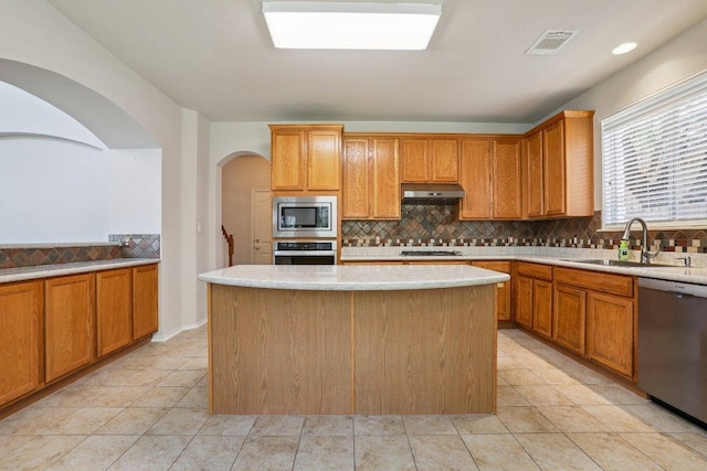 411 S Lynnwood Trl, Cedar Park, TX 78613 - kitchen featuring appliances with stainless steel finishes, under cabinet range hood, tasteful backsplash, a kitchen island, and light tile patterned floors