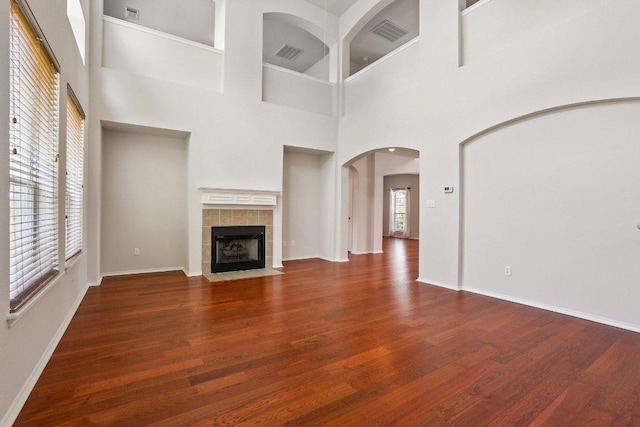 411 S Lynnwood Trl, Cedar Park, TX 78613 - unfurnished living room with wood finished floors, arched walkways, a tile fireplace, and a high ceiling