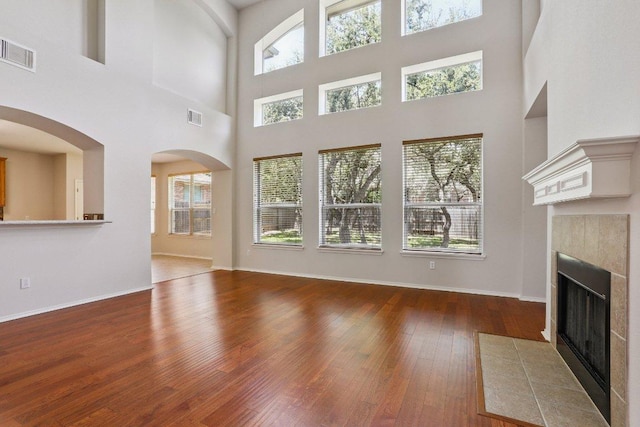 411 S Lynnwood Trl, Cedar Park, TX 78613 - unfurnished living room featuring wood-type flooring, a tile fireplace, a high ceiling, and arched walkways