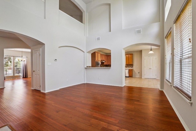 411 S Lynnwood Trl, Cedar Park, TX 78613 - unfurnished living room with light wood finished floors, a chandelier, and a towering ceiling