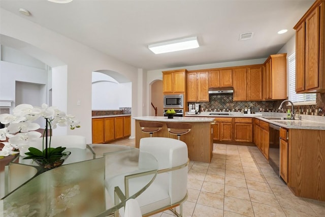 411 S Lynnwood Trl, Cedar Park, TX 78613 - kitchen featuring appliances with stainless steel finishes, under cabinet range hood, backsplash, light countertops, and arched walkways