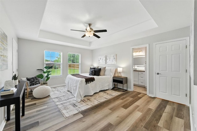 118 W Pauwela Ln, Bastrop, TX 78602 - bedroom featuring a tray ceiling, wood finished floors, ensuite bath, and ceiling fan