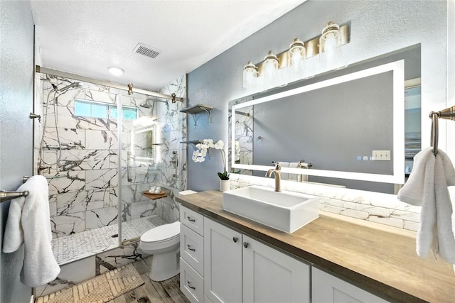 118 W Pauwela Ln, Bastrop, TX 78602 - full bathroom with a marble finish shower, a textured wall, vanity, wood finished floors, and a textured ceiling