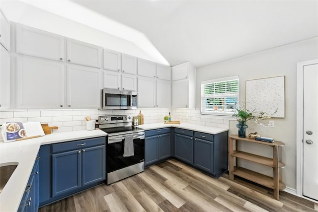 118 W Pauwela Ln, Bastrop, TX 78602 - kitchen featuring appliances with stainless steel finishes, blue cabinetry, lofted ceiling, light wood-type flooring, and backsplash