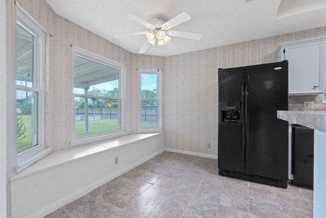 11511 Sombrero Dr, Austin, TX 78748 - kitchen featuring black refrigerator with ice dispenser, white cabinetry, a textured ceiling, ceiling fan, and wallpapered walls
