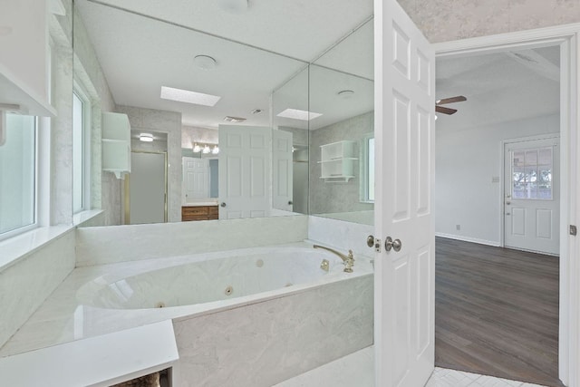 11511 Sombrero Dr, Austin, TX 78748 - full bath featuring a tub with jets, a skylight, a ceiling fan, a shower, and wood finished floors