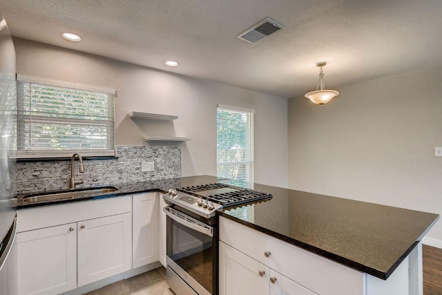 5808 Cherry Park, Austin, TX 78745 - kitchen with stainless steel range with gas stovetop, a peninsula, white cabinets, decorative backsplash, and recessed lighting