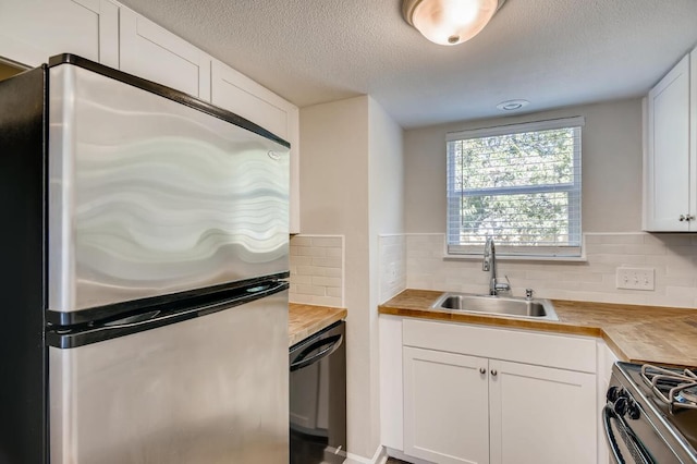 5808 Cherry Park, Austin, TX 78745 - kitchen featuring stainless steel appliances, wooden counters, tasteful backsplash, white cabinets, and a textured ceiling