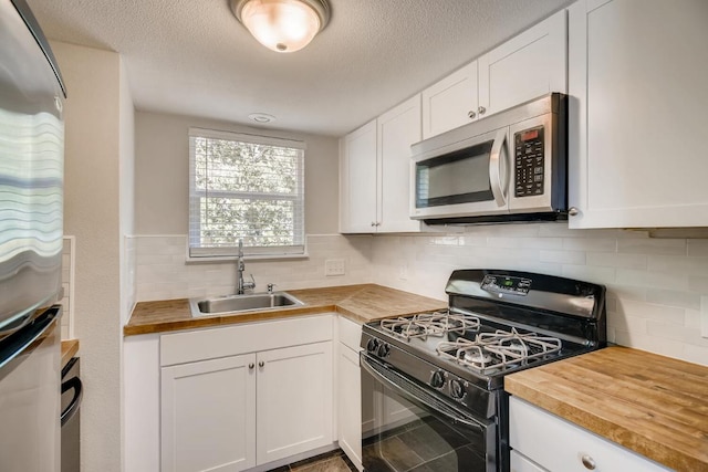5808 Cherry Park, Austin, TX 78745 - kitchen with stainless steel appliances, wood counters, white cabinets, tasteful backsplash, and a textured ceiling