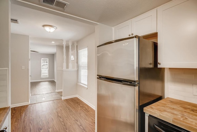 5808 Cherry Park, Austin, TX 78745 - kitchen with freestanding refrigerator, white cabinets, butcher block countertops, light wood finished floors, and backsplash