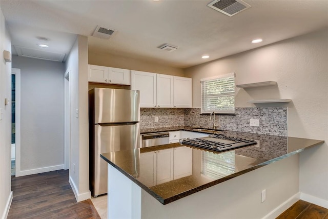 5808 Cherry Park, Austin, TX 78745 - kitchen featuring stainless steel appliances, a peninsula, dark stone countertops, backsplash, and white cabinets