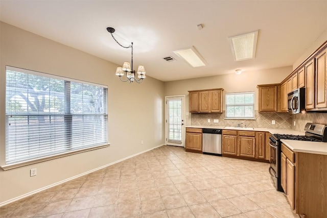 2628 Bolton St, Austin, TX 78748 - kitchen featuring stainless steel appliances, backsplash, a chandelier, brown cabinetry, and light countertops