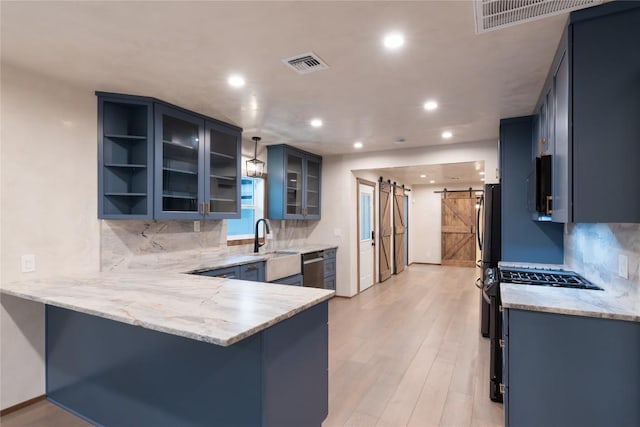 318 W Hackberry St, Fredericksburg, TX 78624 - kitchen with a barn door, a peninsula, light stone counters, backsplash, and recessed lighting