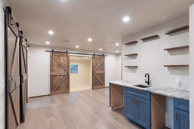318 W Hackberry St, Fredericksburg, TX 78624 - kitchen featuring a barn door, open shelves, blue cabinets, light wood-style flooring, and recessed lighting