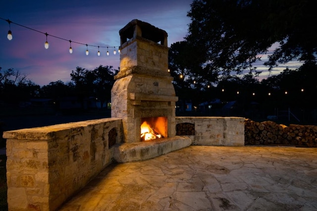 318 W Hackberry St, Fredericksburg, TX 78624 - patio terrace at dusk featuring an outdoor stone fireplace and a patio