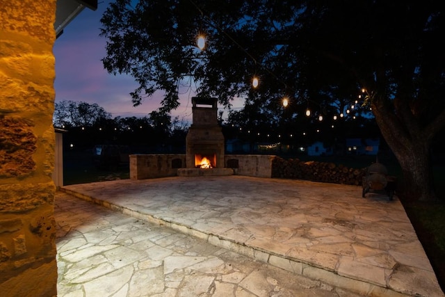 318 W Hackberry St, Fredericksburg, TX 78624 - patio terrace at dusk featuring a lit fireplace and a patio