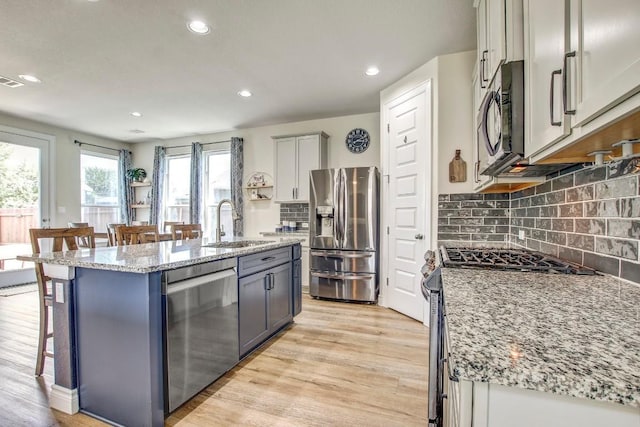 336 Gaida Loop, Georgetown, TX 78628 - kitchen with stainless steel appliances, a kitchen bar, recessed lighting, light stone counters, and decorative backsplash