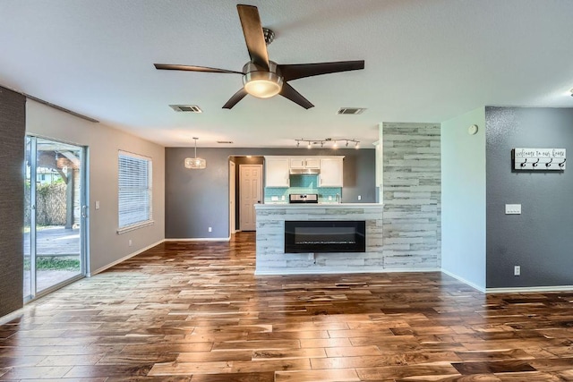 14418 Cummins Way, Manor, TX 78653 - unfurnished living room with dark wood-style floors, ceiling fan, and track lighting