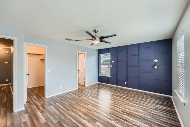 14418 Cummins Way, Manor, TX 78653 - unfurnished bedroom with wood finished floors, multiple windows, a closet, and a spacious closet