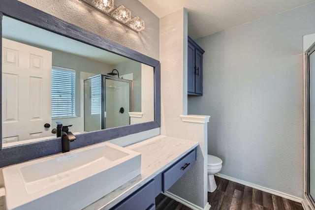 14418 Cummins Way, Manor, TX 78653 - full bathroom with wood finished floors, a shower stall, vanity, and a textured wall