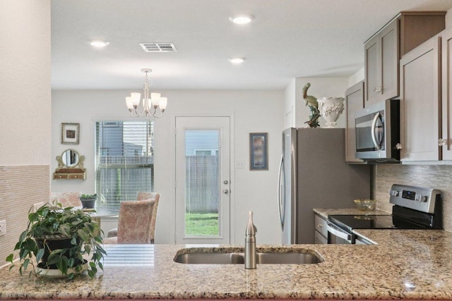 13605 Abigail Adams St, Manor, TX 78653 - kitchen featuring appliances with stainless steel finishes, a chandelier, light stone counters, and recessed lighting