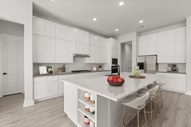 5126 Destination Way, Jonestown, TX 78645 - kitchen featuring stainless steel refrigerator with ice dispenser, backsplash, under cabinet range hood, a kitchen island with sink, and white cabinets