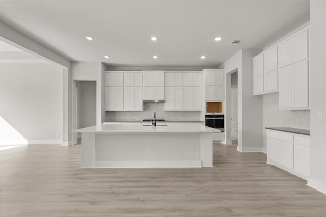 5126 Destination Way, Jonestown, TX 78645 - kitchen with oven, tasteful backsplash, an island with sink, white cabinetry, and recessed lighting