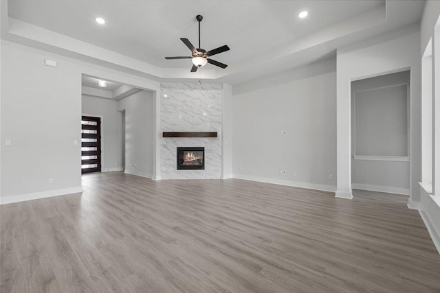 5126 Destination Way, Jonestown, TX 78645 - unfurnished living room featuring a raised ceiling, a ceiling fan, wood finished floors, recessed lighting, and a high end fireplace