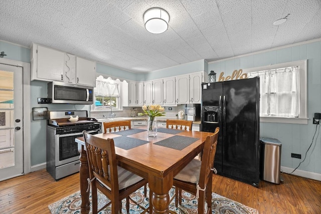707 Wilson St, Taylor, TX 76574 - kitchen with appliances with stainless steel finishes, white cabinets, light wood-style flooring, tasteful backsplash, and crown molding