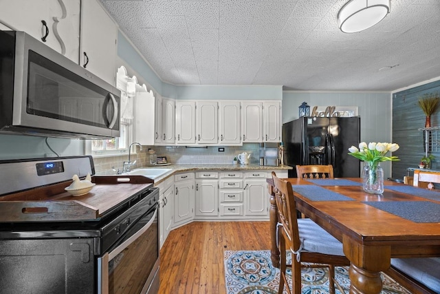 707 Wilson St, Taylor, TX 76574 - kitchen featuring stainless steel appliances, white cabinets, light wood-style flooring, and tasteful backsplash