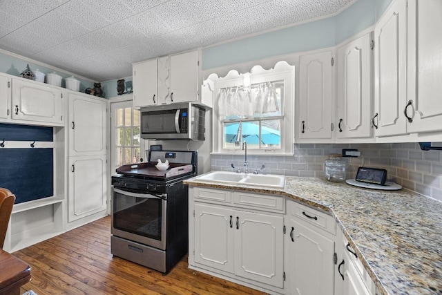 707 Wilson St, Taylor, TX 76574 - kitchen with stainless steel appliances, white cabinetry, and tasteful backsplash