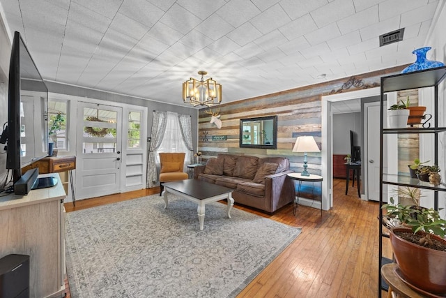 707 Wilson St, Taylor, TX 76574 - living area with wooden walls, light wood-style floors, and a chandelier