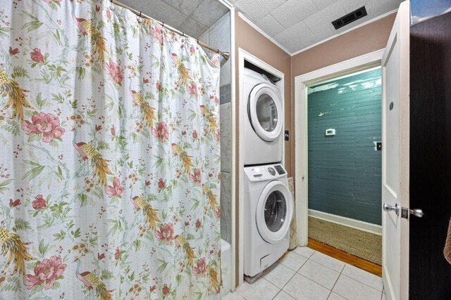 707 Wilson St, Taylor, TX 76574 - washroom with stacked washing machine and dryer, light tile patterned floors, and crown molding