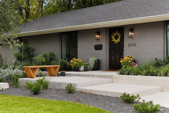 5710 Marilyn Dr, Austin, TX 78757 - view of exterior entry with a shingled roof and brick siding
